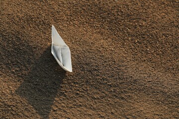 Paper boat on a sandy beach