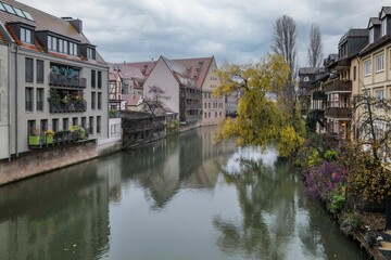 Fototapeta na wymiar Scenic view of old buildings reflecting in a river on a cloudy day in Nuremberg, Germany