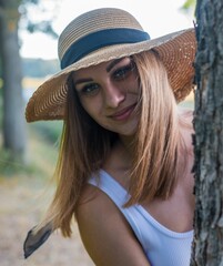 Young adult female in a hat stands in profile in a natural outdoor setting