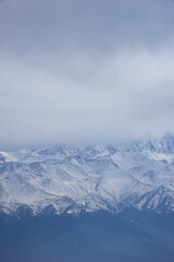 Obraz premium Vertical view of the snow-capped Ten-Zan Bodga peak with clouds floating above it