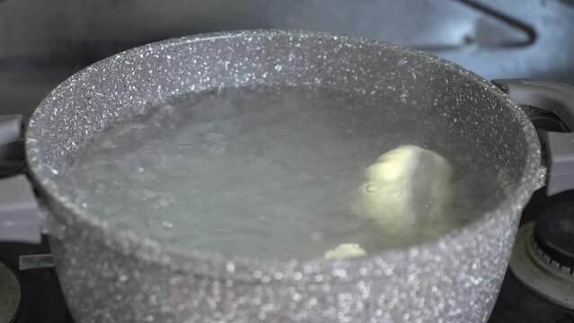 Handmade khinkali in saucepan of boiling water on domestic kitchen