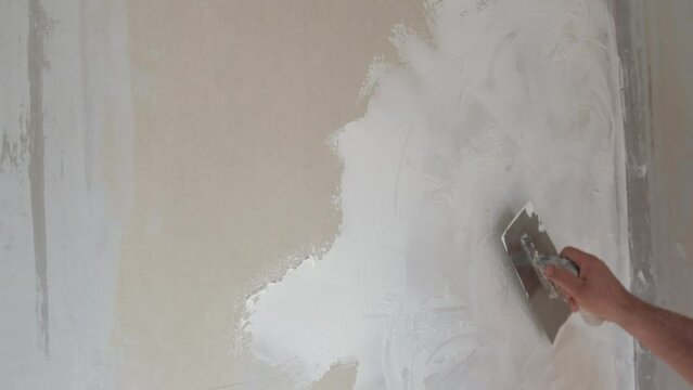 Applying decorative putty. White abstract texture of surface covered with putty. textured background of filler paste applied with putty knife in irregular dashes and strokes. Rough surface plaster