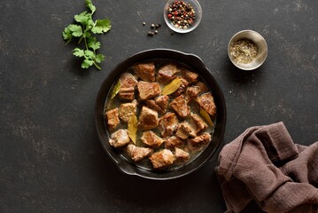 Braised beef in cast iron skillet. Top view, flat lay