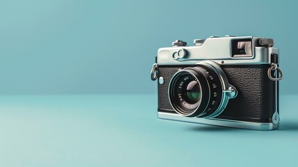 This is a photograph of a vintage camera. The camera is silver and black and has a large lens. It is sitting on a blue background. - obrazy, fototapety, plakaty