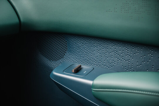 Button to open or close window in door new modern sedan automobile closeup. Gold luxury button in green leather interior in electric car. Supercar interior design detail. Top view. Concept of future.