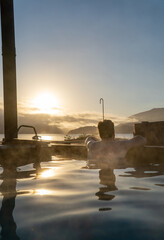 Senior man enjoying in an outdoor hot tub while watching the sunrise over the lake.