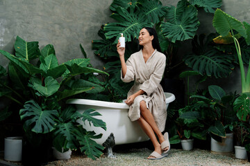 Tropical and exotic spa garden with bathtub in modern hotel or resort with woman in bathrobe...