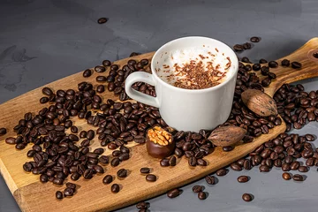Deurstickers Coffee beans and a cup of cappuccino on the background of a dark wooden table. © Vladimir