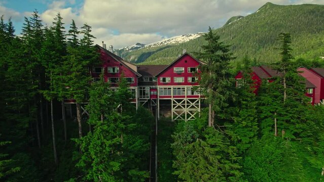 Zoom-in drone shot of red houses with a funicular and trees in front in Ketchikan, Alaska.