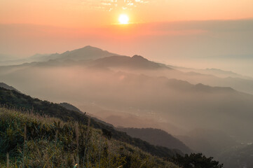 The setting sun casts a veil of mist in vibrant orange hues, creating an expansive tapestry of color on the mountain. Buyan Pavilion, New Taipei City.