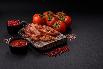 Delicious fresh fried bacon with salt and spices on a dark background
