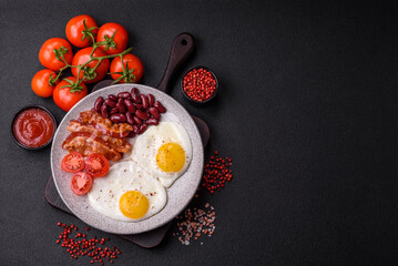 English breakfast with fried eggs, bacon, beans, tomatoes, spices and herbs