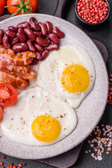 English breakfast with fried eggs, bacon, beans, tomatoes, spices and herbs