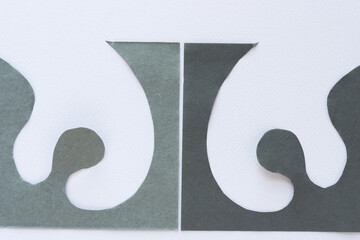 decor shape composed of two pieces of cut gray paper with curvy and wavy elements on blank paper