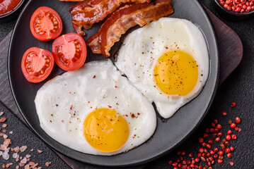 English breakfast with fried eggs, bacon, beans, tomatoes, spices and herbs