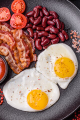 English breakfast with fried eggs, bacon, beans, tomatoes, spices and herbs
