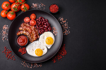 English breakfast with fried eggs, bacon, beans, tomatoes, spices and herbs