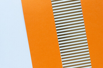 paper background featuring orange solids and scrapbooking paper with gold foil lines alternating with white