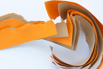 orange and brown card stock torn in half with natural curl on blank paper 