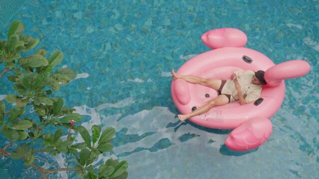 Young man Relaxing on a Pink Flamingo Float in a Pool During Summer