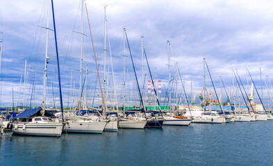 Fototapeta premium boats and yachts on pier in marine city port with masts and bulidings and blue sky on background , water cityscape of urban port