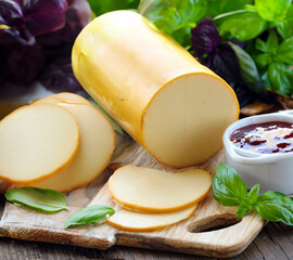 smoked cheese on a wooden board with fresh basil