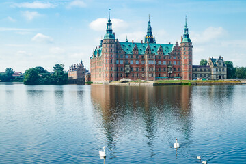 View of Frederiksborg castle with white swans on lake in Hillerod, Denmark