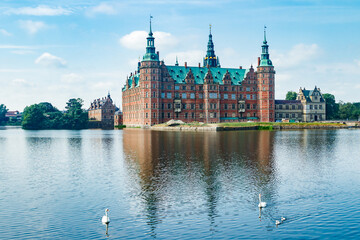 View of Frederiksborg castle with white swans on lake in Hillerod, Denmark