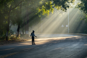 A man stands on a street in the sun, looking to his left - obrazy, fototapety, plakaty