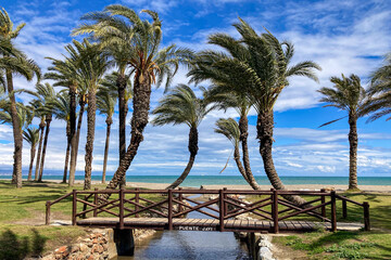 Wooden small bridge on palms and sea background in Torremolinos, Spain