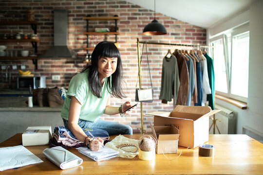 Asian woman packing clothes at home small business environment