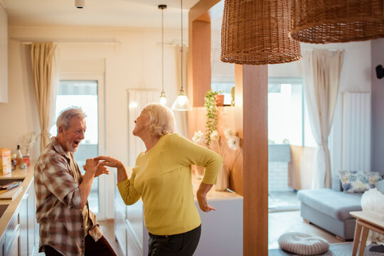 Happy senior couple dancing in the kitchen