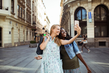 Two women taking a selfie together on a sunny city street