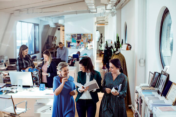 Diverse group of female fashion designers collaborating in a busy design studio