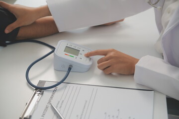 Male doctor uses a blood pressure monitor to check the body pressure and pulse of the patients who come to the hospital for check-ups, Medical treatment and health care concept.