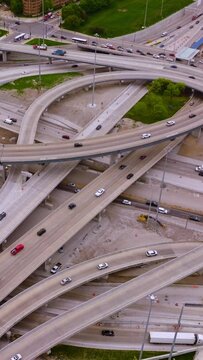 Multiple cars moving quickly by the turns and loops of complicated road system. Road junction in modern Chicago. Top view. Vertical video