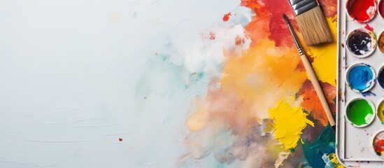 A palette of watercolors, a brush, and a painting on a white background depicting a sky filled with...