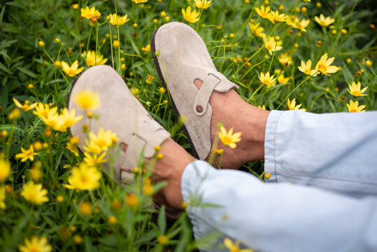 Close-up of man's feet in beige Birkenstock Boston among flowers on March 16, 2024, in Bangkok, Thailand.