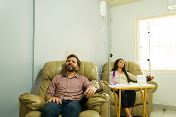 Relaxed man and woman restoring their health getting IV drip vitamin therapy - obrazy, fototapety, plakaty