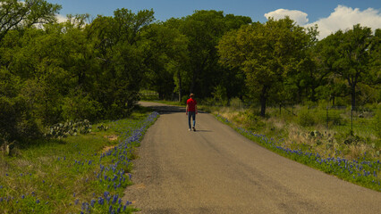 Person walking on road lined with Texas bluebonnets