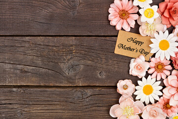Happy Mothers Day gift tag with paper flower side border. Above view on a dark wood background. Copy space. - 771654922