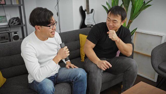 Two asian men singing and enjoying time together in a cozy living room setting.