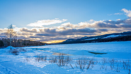 Idyllic snowy landscape with a view of clouds colored by the sun