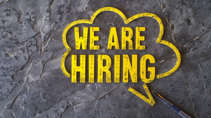 A speech bubble with the text "WE ARE HIRING" on a textured metallic background signifies a job opportunity.