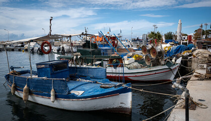 Fishing boats in the harbor, nice blue sky and clouds at the background.