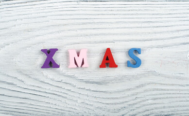 XMAS word on wooden background composed from colorful abc alphabet block wooden letters, copy space for ad text. Learning english concept.