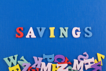 SAVINGS word on blue background composed from colorful abc alphabet block wooden letters, copy space for ad text. Learning english concept.