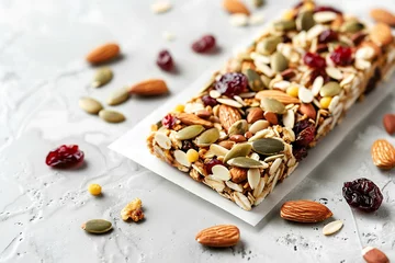 Tuinposter granola bar richly topped with whole almonds, pumpkin seeds, and dried cranberries, on the white ceramic countertop © Vina