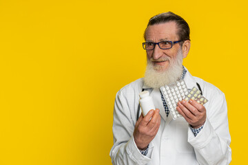 Senior doctor cardiologist man shows lot of tablet pills in blisters recommends drugs vitamin...
