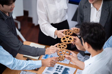 Office worker holding cog wheel as unity and system teamwork in corporate workplace with piles of...
